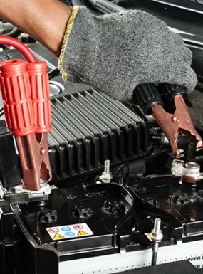 Mechanic connecting jumper cables to a car battery for fast roadside charge