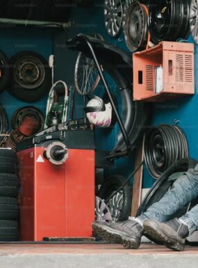 Mechanic inspecting spare tire in car trunk